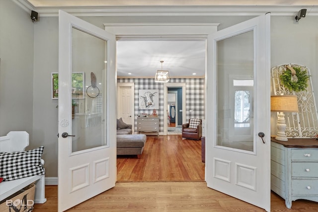 entryway featuring wallpapered walls, ornamental molding, light wood finished floors, and french doors