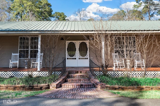 view of exterior entry featuring covered porch and metal roof