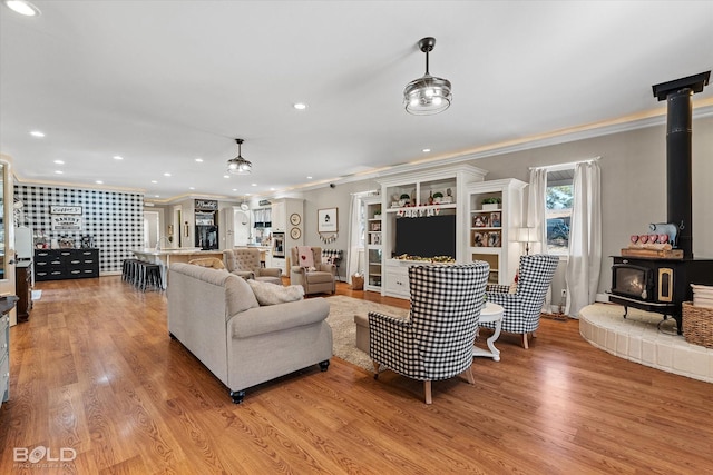 living room featuring a wood stove, light wood-style floors, ornamental molding, and recessed lighting