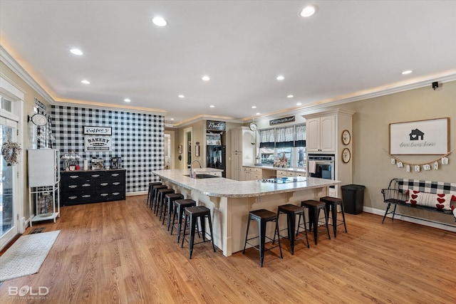 kitchen with a spacious island, light wood-style flooring, a kitchen bar, and oven