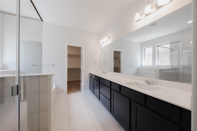 full bathroom with a spacious closet, visible vents, a sink, a stall shower, and double vanity