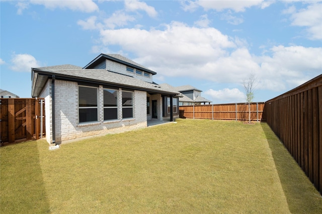 back of house with brick siding, a fenced backyard, and a lawn