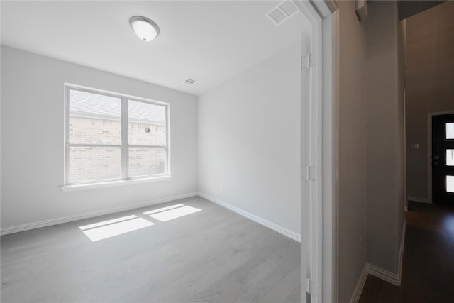 unfurnished room with visible vents, baseboards, and wood finished floors