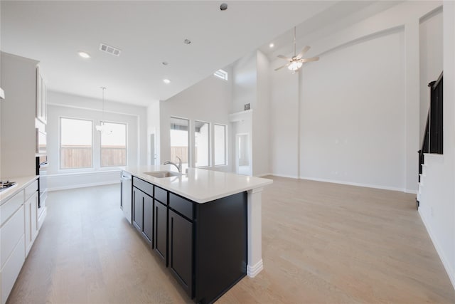 kitchen featuring light wood-style floors, visible vents, a sink, light countertops, and oven