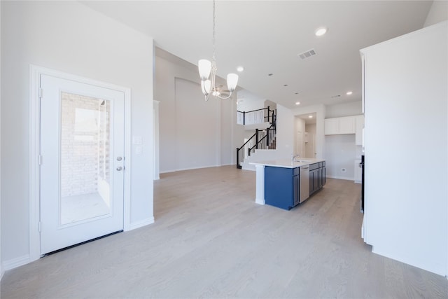 kitchen with light wood-type flooring, white cabinetry, light countertops, hanging light fixtures, and a notable chandelier