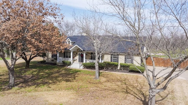 new england style home with fence, a porch, and a front yard