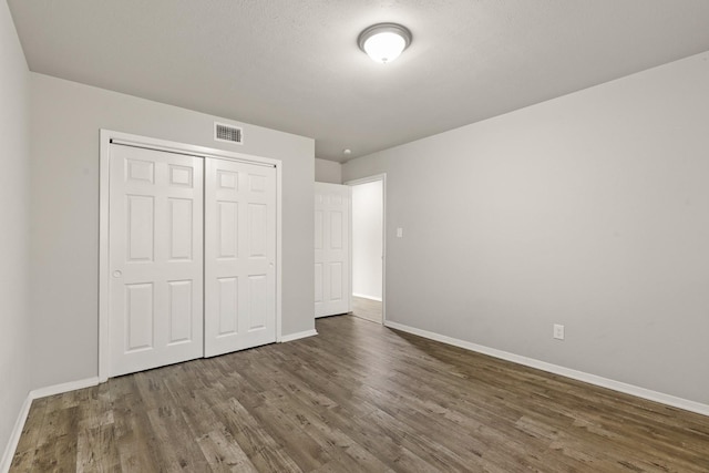 unfurnished bedroom featuring dark hardwood / wood-style floors and a closet