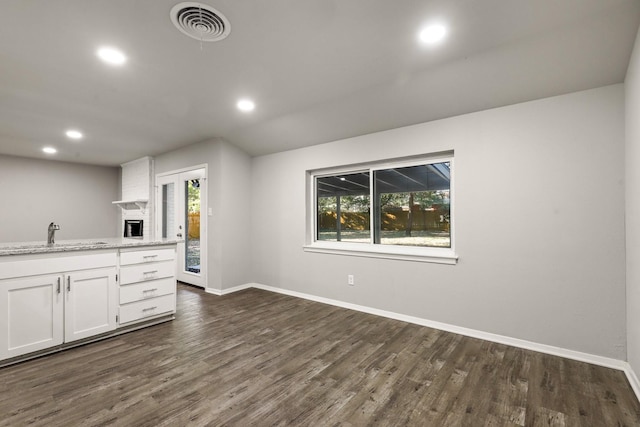 kitchen featuring sink, light stone counters, dark hardwood / wood-style floors, a wealth of natural light, and white cabinets