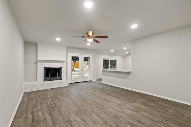 unfurnished living room featuring french doors, ceiling fan, dark hardwood / wood-style flooring, and a brick fireplace