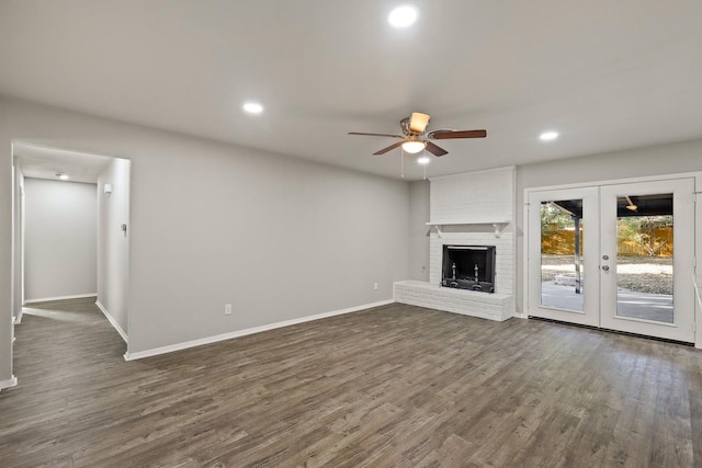 unfurnished living room with dark wood-type flooring, ceiling fan, a fireplace, and french doors