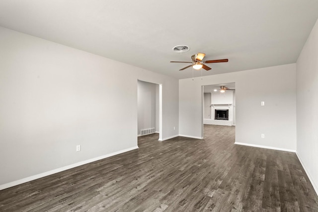 unfurnished living room featuring a brick fireplace, dark hardwood / wood-style floors, and ceiling fan