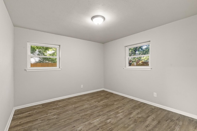 spare room with a healthy amount of sunlight, dark hardwood / wood-style floors, and a textured ceiling