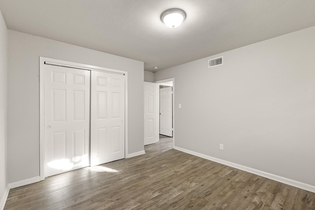 unfurnished bedroom with dark hardwood / wood-style flooring and a closet