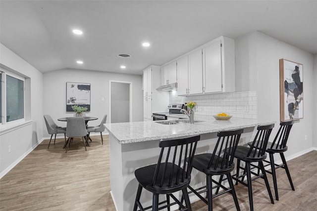 kitchen with sink, light hardwood / wood-style flooring, a breakfast bar area, white cabinets, and kitchen peninsula