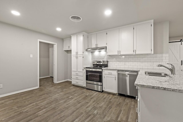 kitchen featuring white cabinetry, wood-type flooring, sink, stainless steel appliances, and a barn door