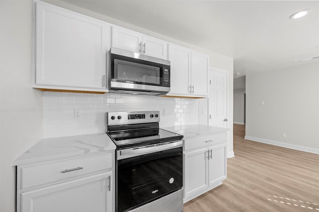 kitchen with light stone counters, appliances with stainless steel finishes, backsplash, and white cabinets