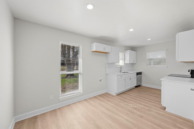 kitchen with sink, dishwasher, range, white cabinetry, and light hardwood / wood-style floors