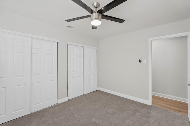 unfurnished bedroom with multiple closets, carpet floors, and ceiling fan