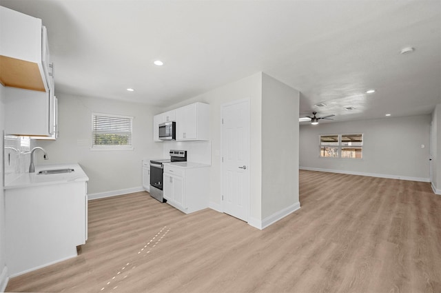 kitchen featuring sink, light wood-type flooring, ceiling fan, stainless steel appliances, and white cabinets