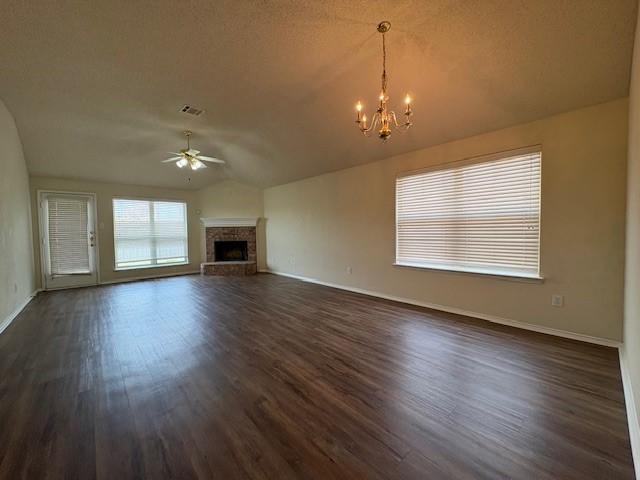 unfurnished living room with vaulted ceiling, dark hardwood / wood-style flooring, ceiling fan with notable chandelier, and a textured ceiling