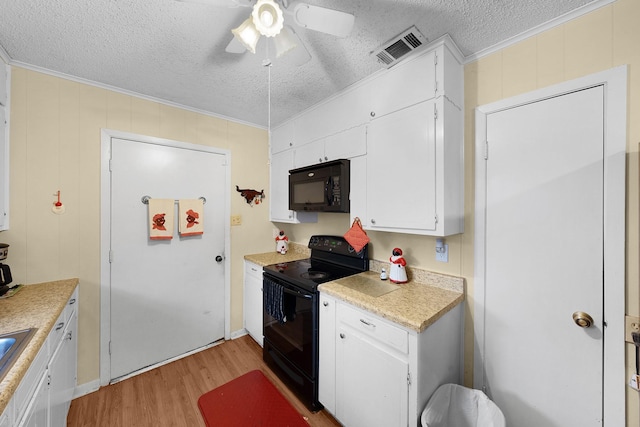 kitchen featuring ornamental molding, black appliances, a textured ceiling, white cabinets, and light wood-type flooring