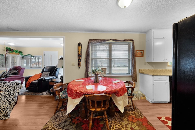 dining space featuring ornamental molding, a textured ceiling, and light hardwood / wood-style floors