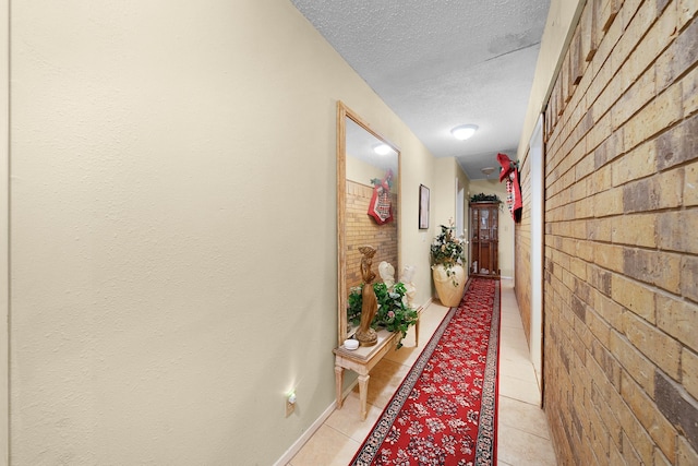 corridor featuring brick wall and a textured ceiling