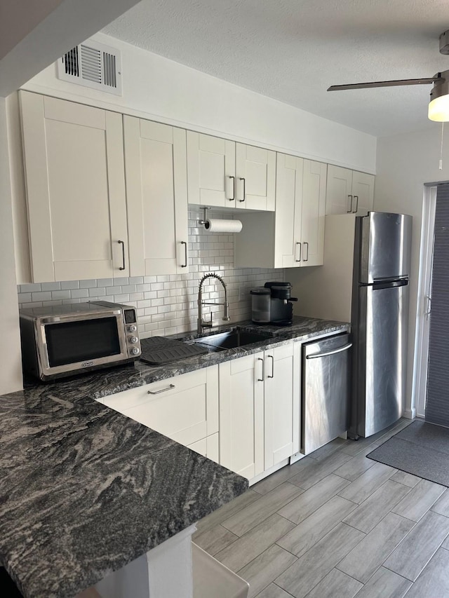 kitchen with sink, white cabinetry, ceiling fan, stainless steel appliances, and backsplash