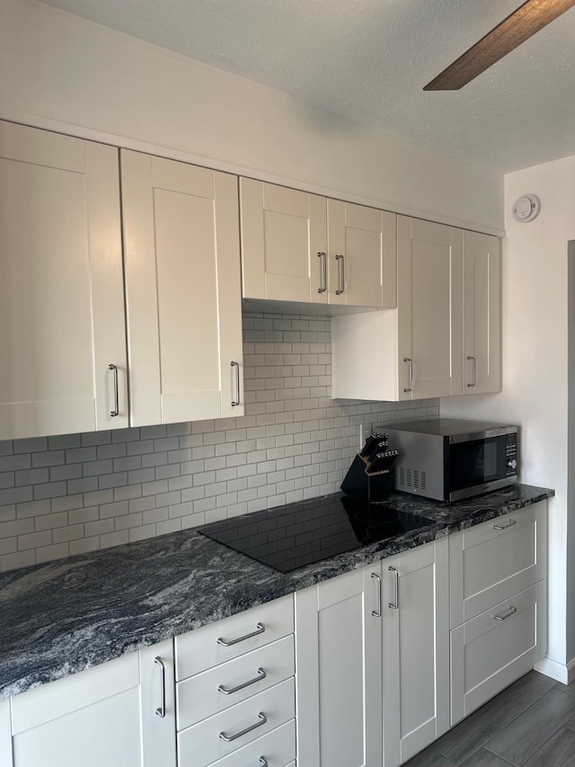 kitchen featuring black electric cooktop, a textured ceiling, tasteful backsplash, and white cabinets