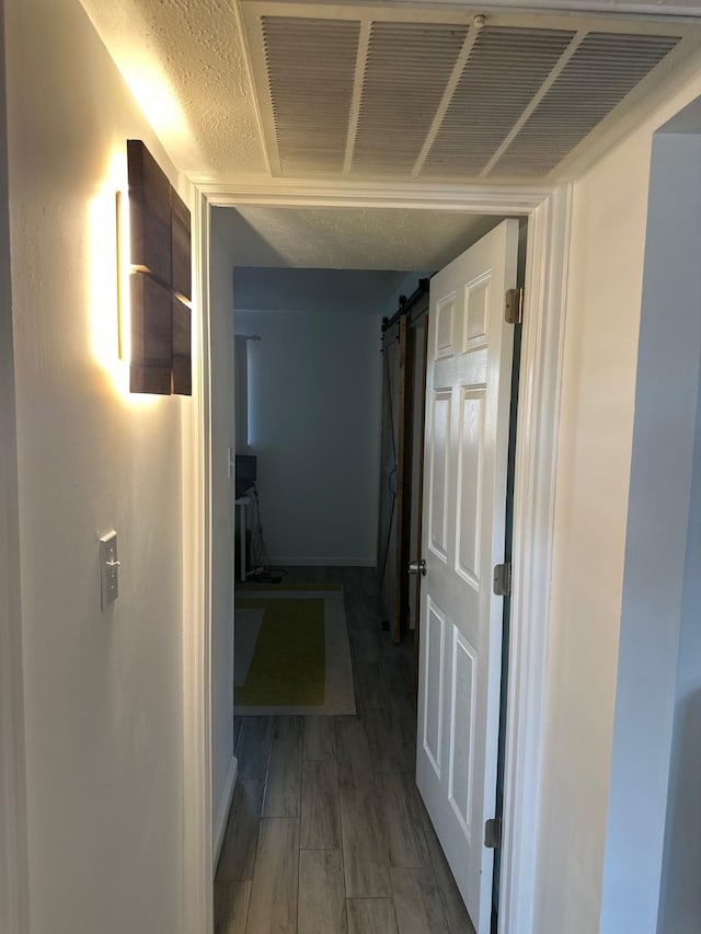 hallway featuring a barn door and dark wood-type flooring