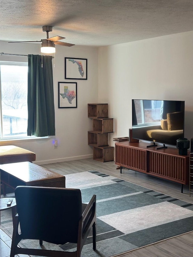 living room featuring ceiling fan, wood-type flooring, and a textured ceiling