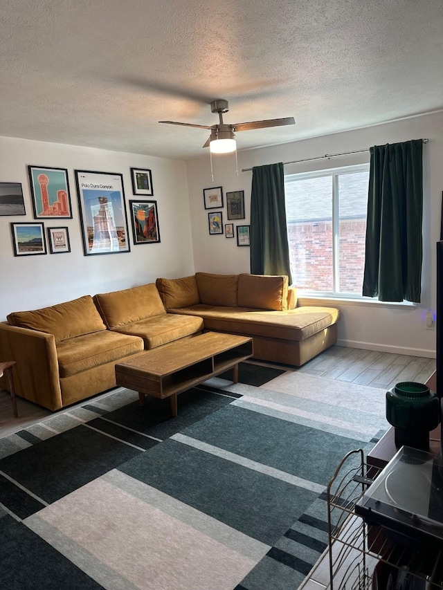 living room featuring ceiling fan, wood-type flooring, and a textured ceiling