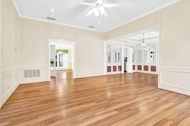 spare room featuring ceiling fan with notable chandelier, light hardwood / wood-style flooring, and ornamental molding