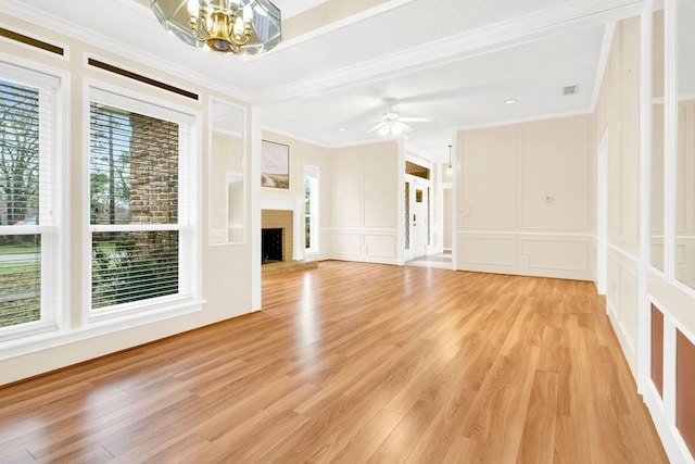 unfurnished living room with a brick fireplace, crown molding, light hardwood / wood-style floors, and a healthy amount of sunlight