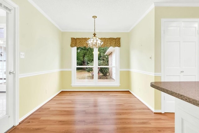 unfurnished dining area with ornamental molding, a notable chandelier, and light wood-type flooring