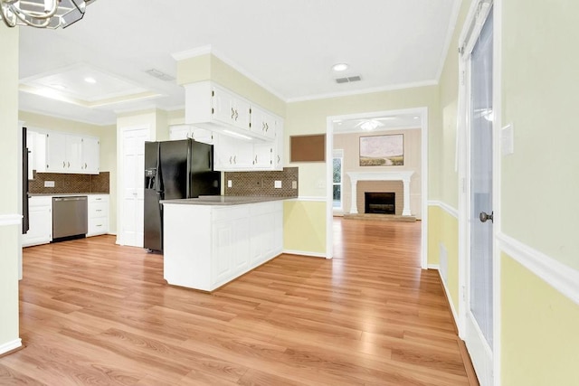 kitchen featuring white cabinets, ornamental molding, stainless steel dishwasher, black fridge, and light hardwood / wood-style flooring