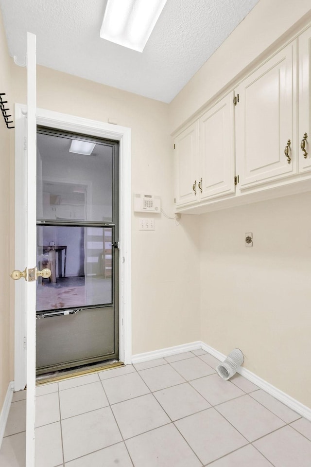 washroom with light tile patterned flooring, cabinets, hookup for an electric dryer, and a textured ceiling