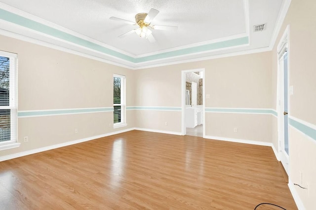 unfurnished room with ornamental molding, a raised ceiling, and light wood-type flooring