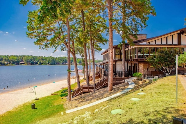 view of play area featuring a water view, a beach view, and a lawn