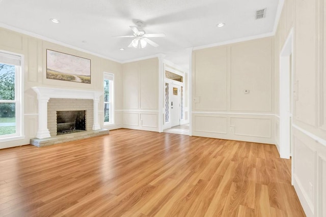 unfurnished living room with ornamental molding, a brick fireplace, and a healthy amount of sunlight