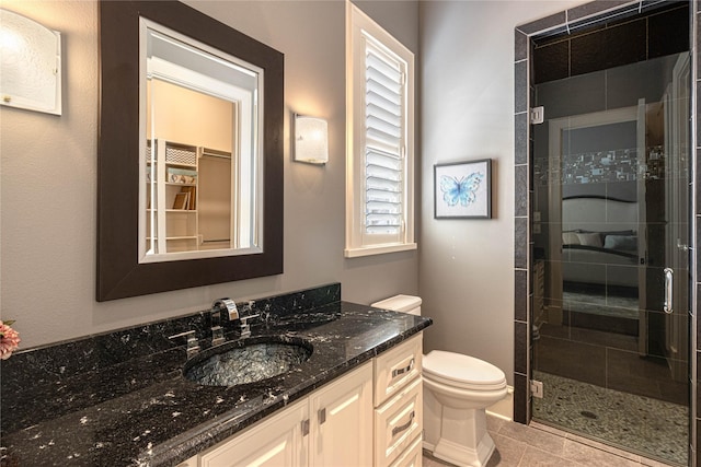 bathroom featuring walk in shower, vanity, toilet, and tile patterned flooring