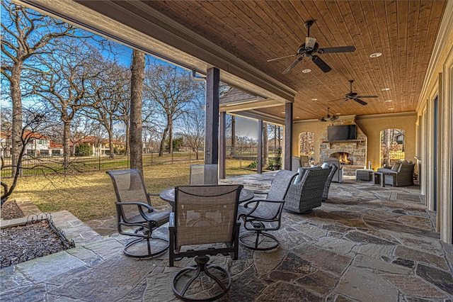 view of patio / terrace featuring ceiling fan and an outdoor stone fireplace