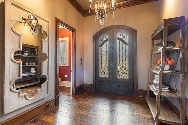 foyer entrance featuring crown molding, dark hardwood / wood-style floors, a notable chandelier, and french doors