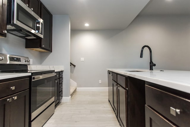 kitchen with stainless steel appliances, sink, and light wood-type flooring