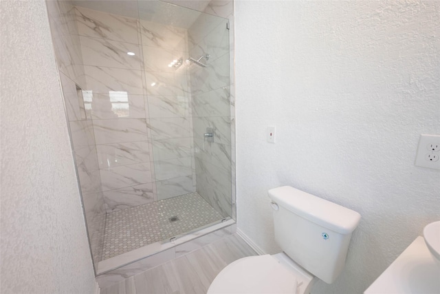 bathroom with a tile shower and toilet