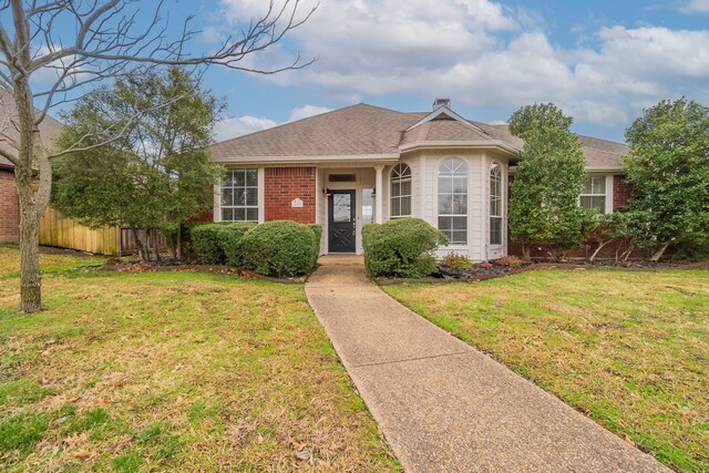 view of front of house featuring brick siding, a front lawn, a chimney, and fence