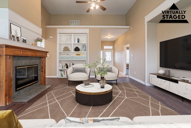 living area with baseboards, a tiled fireplace, visible vents, and dark wood-type flooring