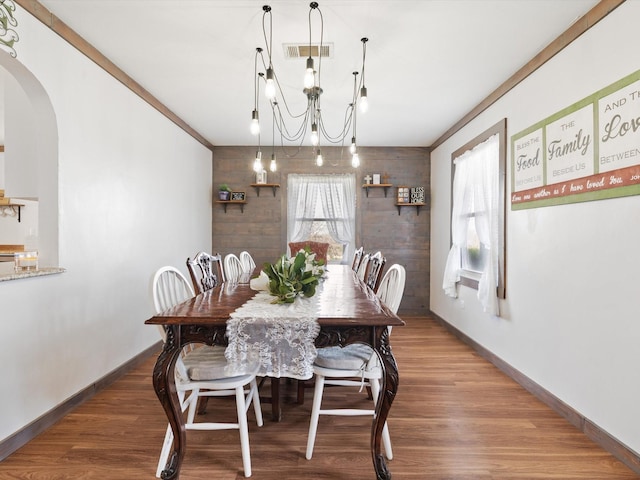 dining room with crown molding, wood-type flooring, and a notable chandelier