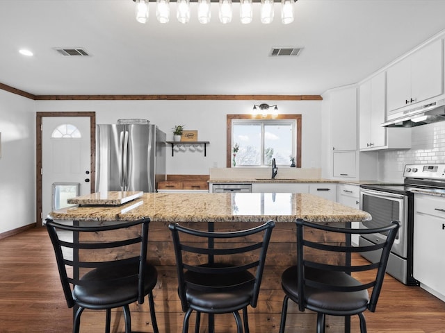 kitchen featuring sink, a breakfast bar, appliances with stainless steel finishes, white cabinetry, and a kitchen island