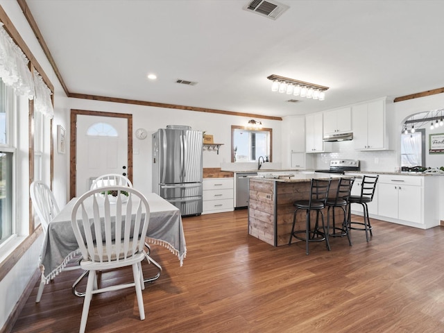 kitchen featuring white cabinetry, dark hardwood / wood-style flooring, stainless steel appliances, and a center island